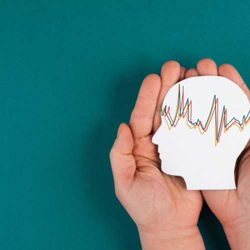 Holding a head in the hands, mental health concept, alzheimer and epilepsy disorder, brain waves, paper cut out