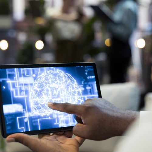 Close up of employee using tablet touchscreen to interact with AI assistant software interface. Businessperson analyzing neural network data on device display at work