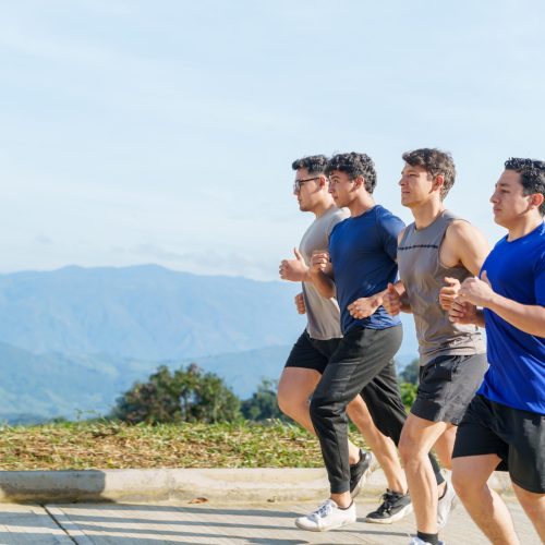 Group of friends running together on scenic mountain road, promoting teamwork and outdoor fitness, healthy lifestyle and exercise concept