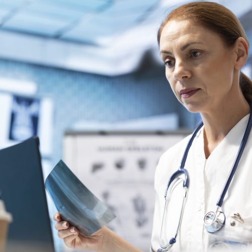 In a treatment center, physician reviewing radiography data on a scan and putting a diagnostic. Medical expert analyzing x rays and test results, developing treatment options and disease prevention.